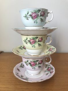 three stacked tea cups and saucers with pink roses on them, one is blue