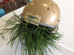 a football helmet sitting on top of a table covered in green grass next to blue chairs