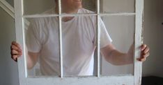 a man is looking through a window with bars on the sides and his hands are in front of him