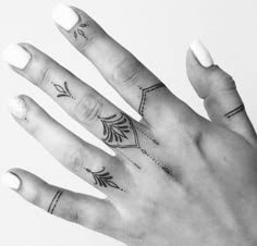 a woman's hand with tattoos on it and an arrow tattooed on the middle finger