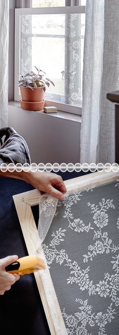 a person is working on a piece of fabric in front of a window with a pair of scissors