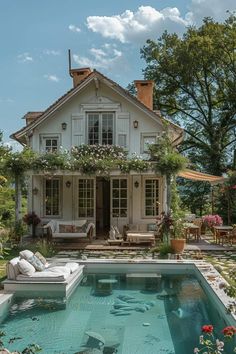 a pool in front of a house with flowers growing on the roof and around it