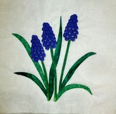 three blue flowers on white paper with green stems and leaves in the center, sitting next to each other