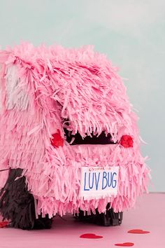 a pink car covered in fake feathers on top of a table