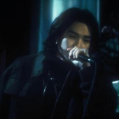 a man with long hair holding a microphone in his hand and wearing a leather jacket