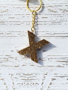 a gold star shaped keychain hanging on a white wooden background with the word love written in it