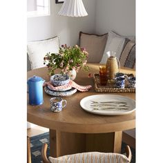 a wooden table topped with plates and vases next to a lamp hanging from the ceiling