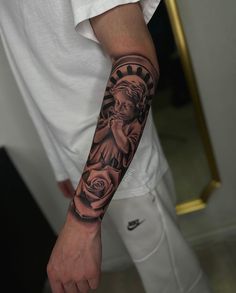 a man's arm with a statue of liberty and roses tattoo on his left arm