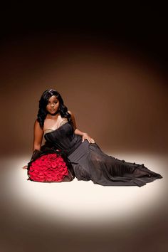 a woman is sitting on the floor in a black and red dress with her legs spread out