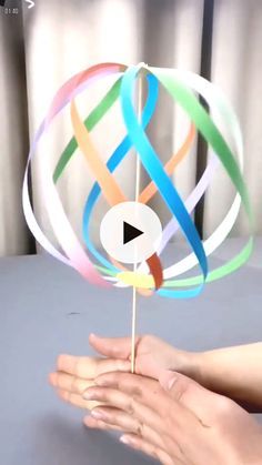 a hand holding a multicolored lollipop on top of a blue table