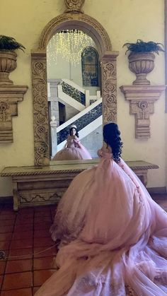 a woman in a pink dress looking into a mirror