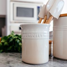 a kitchen counter with two white ceramic containers and utensils on top of it