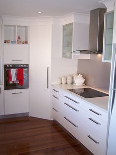 a kitchen with white cabinets and wood floors