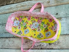 a yellow and pink flowered bag hanging on a wooden wall