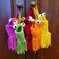 four crocheted purses hanging on a door handle with eyes painted on them