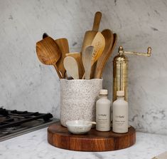 kitchen utensils and wooden spoons in a cup on a marble counter top