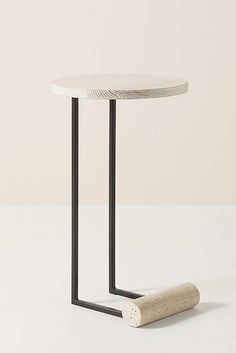 a white table with black metal legs and a cork on the floor next to it