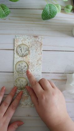 two hands are holding an old clock on a piece of paper with leaves around it