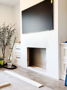 a tv mounted on the wall above a fireplace in a room with white walls and wood flooring