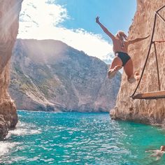 a woman jumping into the water from a cliff