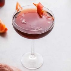 a close up of a drink in a glass with orange peels on the rim