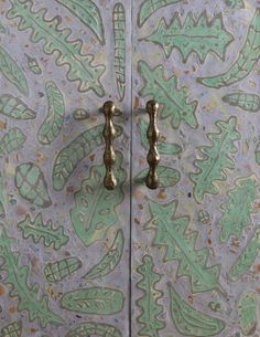 the door is decorated with green and white designs on it's sides, while two brass handles are visible in the background