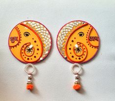 two orange and white earrings with beaded details on each earring, one in the shape of an elephant's head