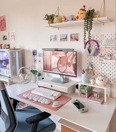 a desk with a computer, keyboard and phone on it in front of a wall full of pictures