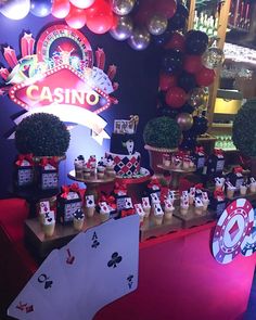 a casino themed party with cards and balloons on the wall, tables set up in front of them