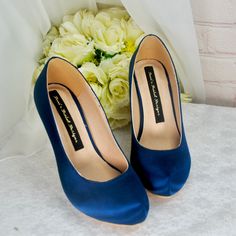 a pair of blue high heels sitting next to a bouquet of flowers