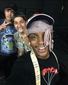 three young men posing for the camera with one wearing a hat and holding his hand up