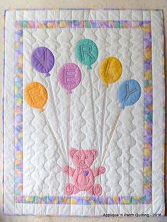 a quilted wall hanging with balloons in the shape of letters and a teddy bear