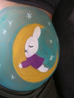 a pregnant woman's belly painted with an image of a rabbit on the moon