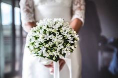 a bride holding a bouquet of white flowers