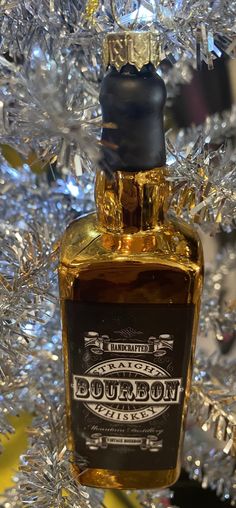 a bottle of bourbon sitting on top of a table next to a silver tinsel tree