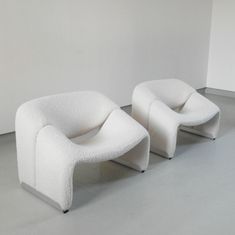 two white chairs sitting next to each other in a room with no one on the floor