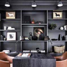 an office with black shelves and leather chairs