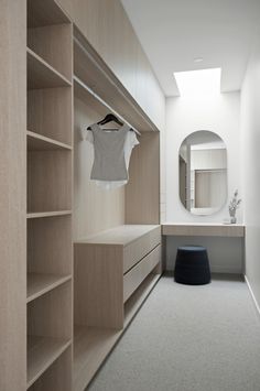 an empty walk - in closet with shelves and clothes hanging on the wall, next to a round mirror