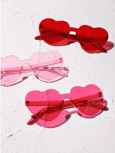 three heart shaped glasses are sitting on a white surface with pink and red hearts attached to them