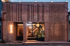 a brick building with lots of windows and lights on the outside, along with potted plants