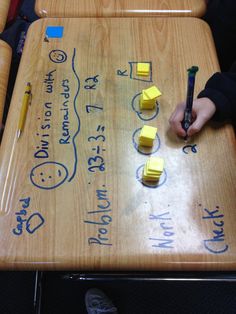 someone is writing on a wooden table with sticky notes