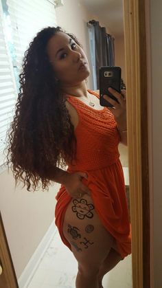 a woman in an orange dress taking a selfie