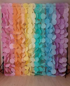 the backdrop is made up of many different colored paper circles and stands in front of a wall