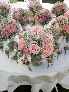 a bunch of pink flowers sitting on top of a white table cloth covered tablecloth