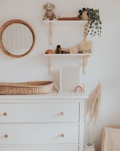 a baby's room with a dresser, mirror and teddy bear on the wall