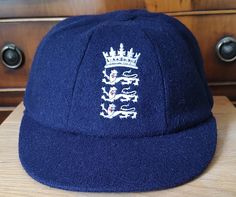 Traditional Style England Three Lions Crest Navy Blue Woollen Cricket Caps. The caps come in two sizes, large that fits a head size of up to 60 cms, and XL, that fits up to 62 cms. An elasticated insert is fitted, to help ensure a comfortable fit. Embroidered with the famous England three lions cricket crest. Price only £18.95p each, please select your required size when you place your order ! Classic Blue Hats For Sports Events, Classic Blue Hat For Sports Events, Navy Winter Baseball Cap, Blue Curved Brim Baseball Cap For Winter, Winter Blue Baseball Cap One Size, Blue Winter Baseball Cap, One Size Fits Most, Winter Blue Baseball Cap One Size Fits Most, Vintage Navy Flat Cap, Blue One Size Flat Cap Baseball Cap