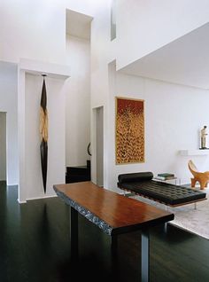 a living room filled with furniture and a large painting on the wall next to a wooden table