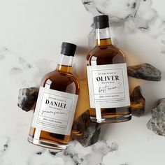 two bottles of oil sitting on top of a marble counter next to rocks and stones