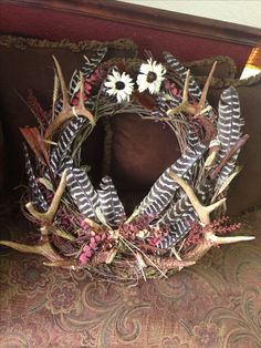 a wreath made out of antlers and flowers is sitting on a couch with a pillow