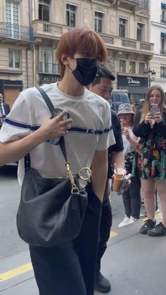 a person wearing a face mask and holding a cell phone while walking down the street